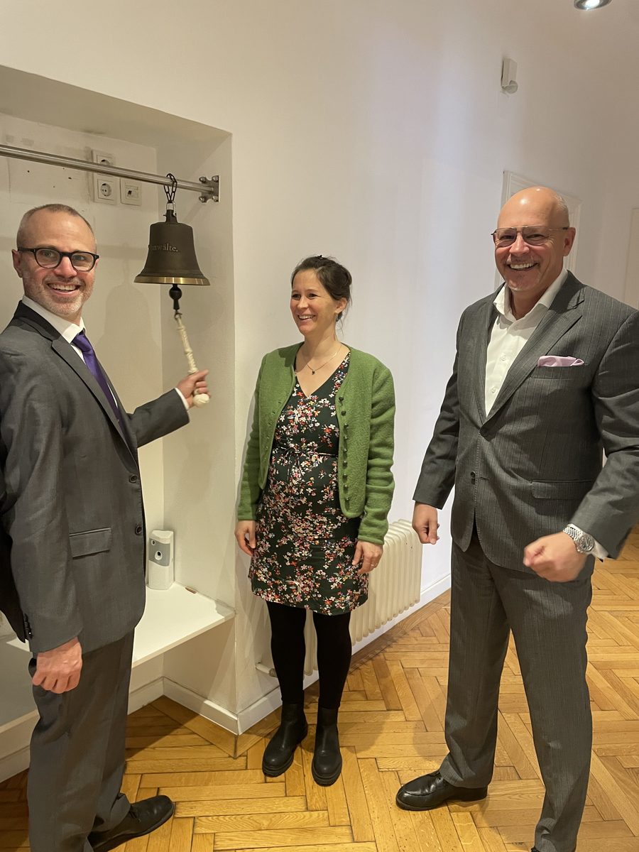 Mandant Matthew mit dem Team von Team-Anwälte beim Läuten der Kanzlei-Glocke nach erfolgreichem Verfahrensabschluss
